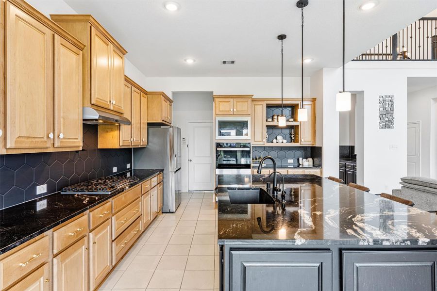 Gorgeous kitchen comes equipped with stainless steel appliances, beautiful natural wood cabinetry, granite countertops, a large eat-in island, 100 percent sink with drinking water and soap fixtures, a great sized pantry tucked behind the stove, and a pot filler over the stove for convenience.