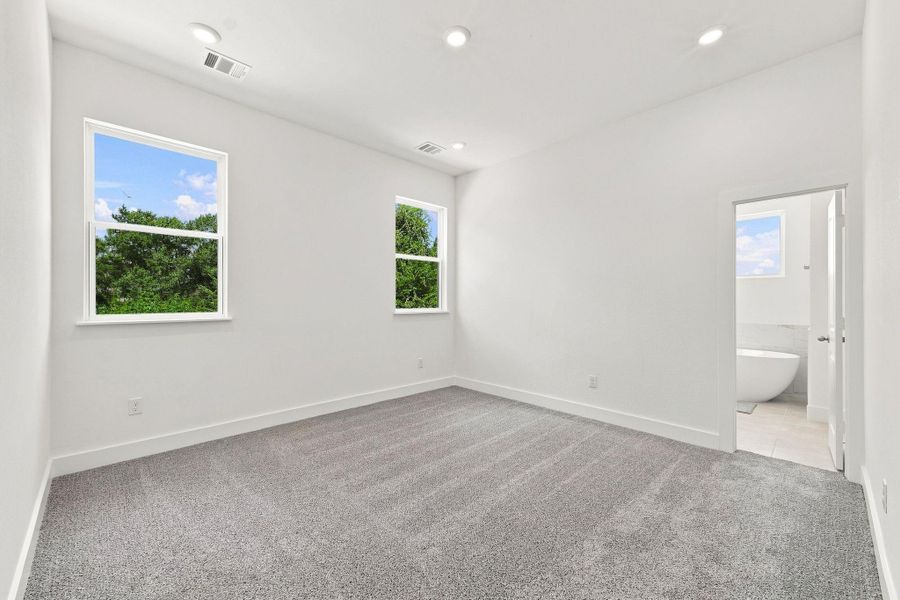 Spacious primary bedroom with high ceiling, recessed lighting, natural light, and plenty of room for a complete bedroom suite. Spacious primary bedroom with high ceiling, recessed lighting, natural light, and plenty of room for a complete bedroom suite.