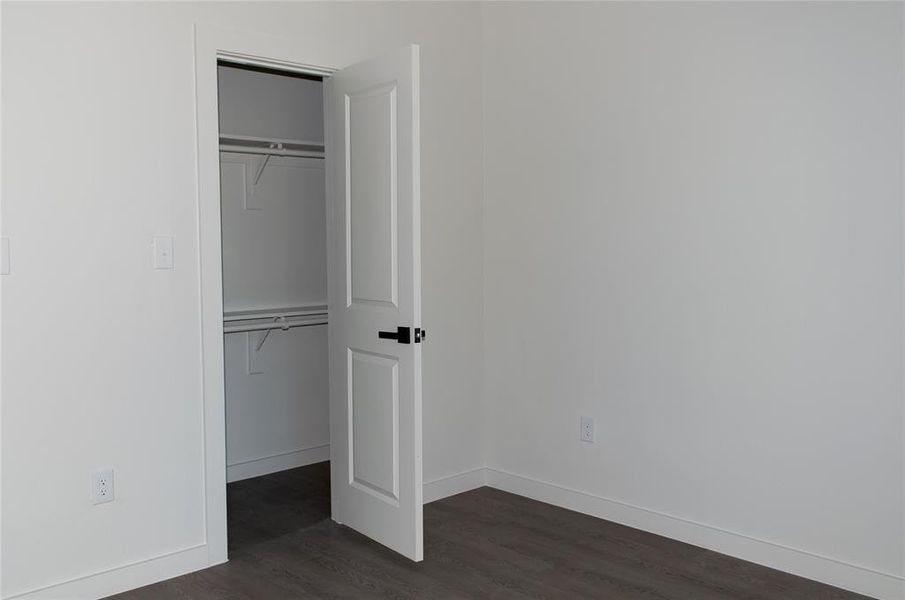 Unfurnished bedroom with a closet and dark wood-style floors Unfurnished bedroom with a closet and dark wood-style floors