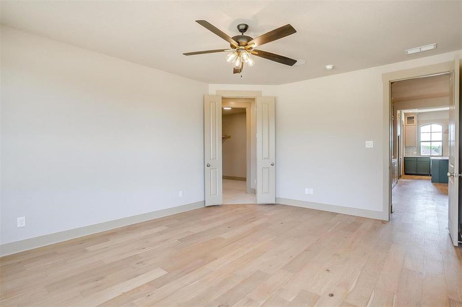 Unfurnished room featuring light wood-style floors, ceiling fan, visible vents, and baseboards