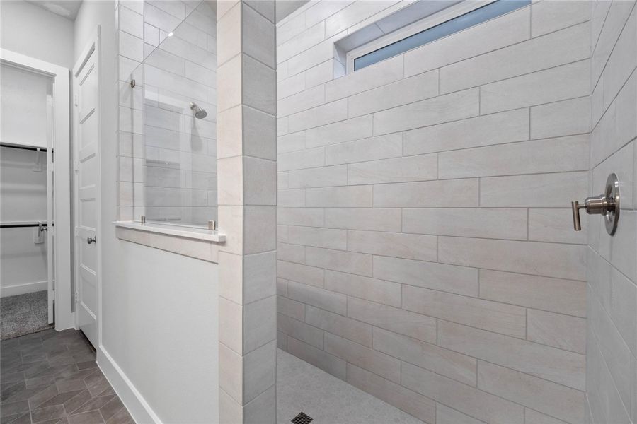 This walk-in shower with stylish tile surround is designed with a clean and modern aesthetic. A clear, frameless glass panel acts as a partial enclosure for the walk-in shower, which helps to keep water splashes contained while maintaining an open, airy feel to the rest of the bathroom.
