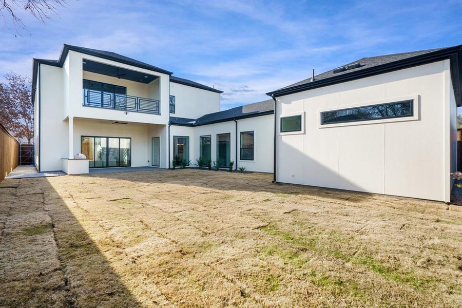 Rear view of house featuring a balcony and a yard