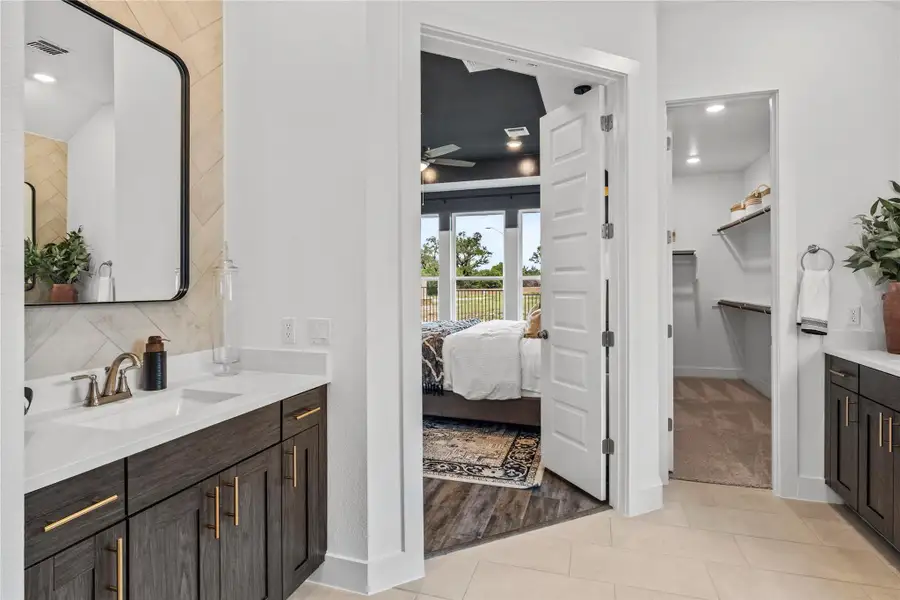 Full bath with vanity, tile patterned floors, ceiling fan, a walk in closet, and ensuite bath