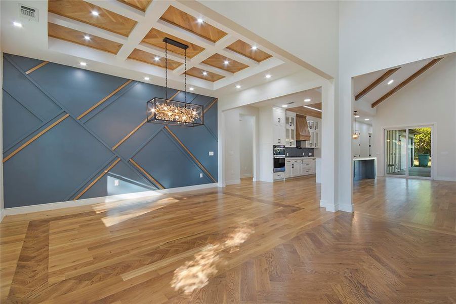 Unfurnished living room featuring beam ceiling, a chandelier, a towering ceiling, parquet floors, and recessed lighting
