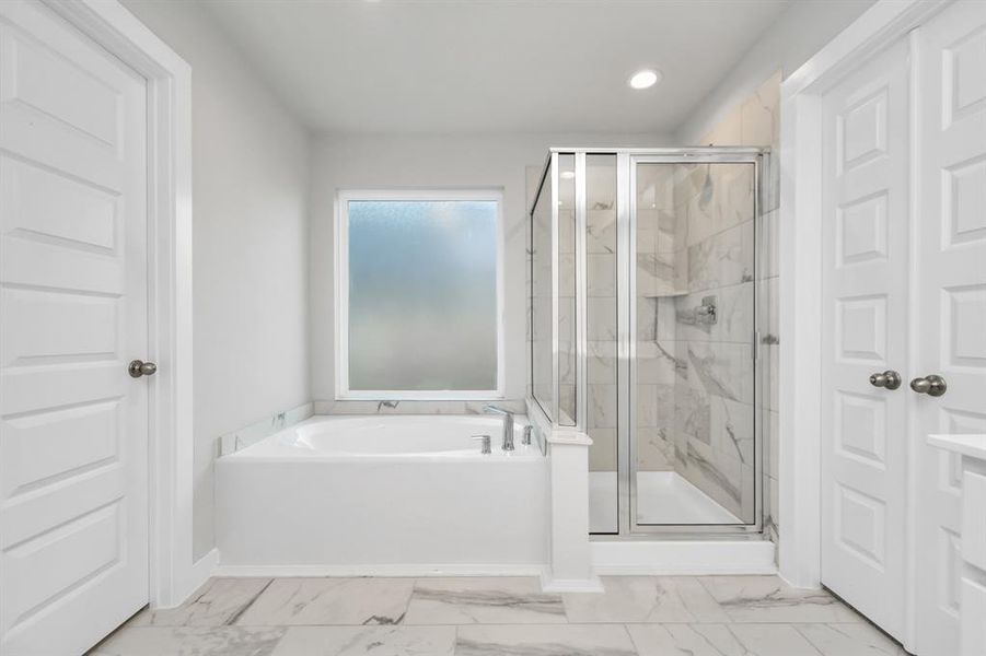 The primary en-suite has a soaking tub to give you that spa experience. The large privacy window allow lots of nature light in the space. Sample photo of completed home with similar floor plan. As-built interior colors and selections may vary.