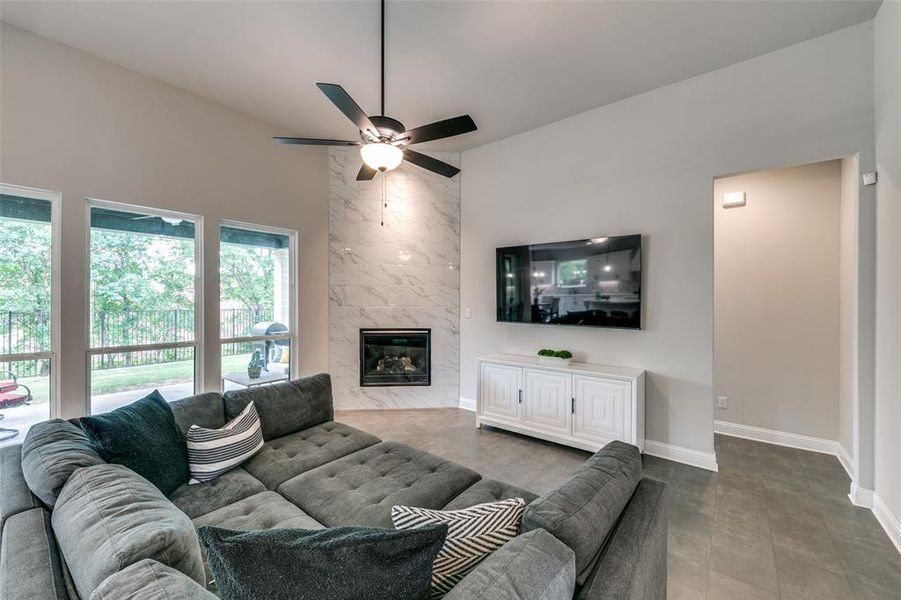 Living room featuring tile floors, ceiling fan, and a high end fireplace