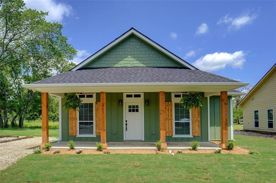 View of front of property featuring a porch and a front yard