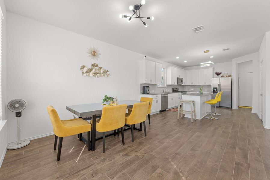 Dining room featuring a notable chandelier, wood finished floors, visible vents, and baseboards