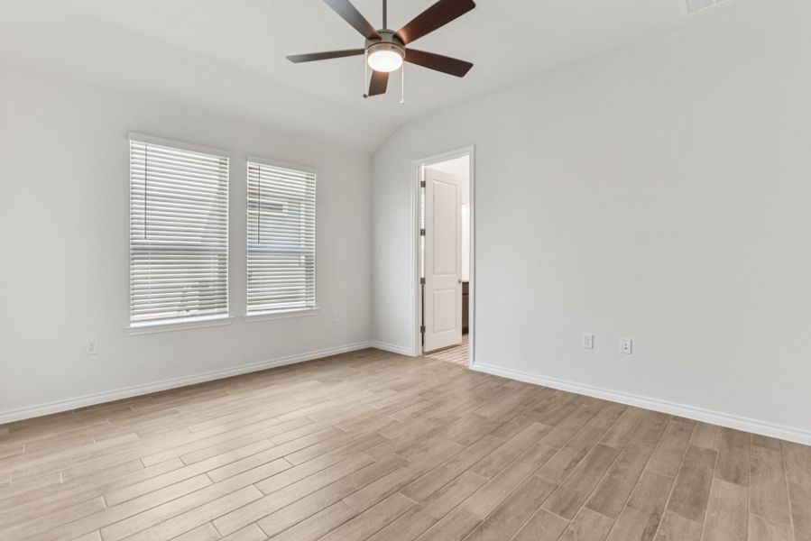Empty room featuring lofted ceiling, light wood finished floors, and ceiling fan Empty room featuring lofted ceiling, light wood finished floors, and ceiling fan