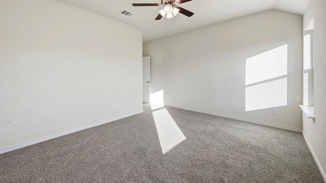 Spacious room featuring vaulted ceilings, neutral-toned carpeting, and a ceiling fan with integrated lighting
