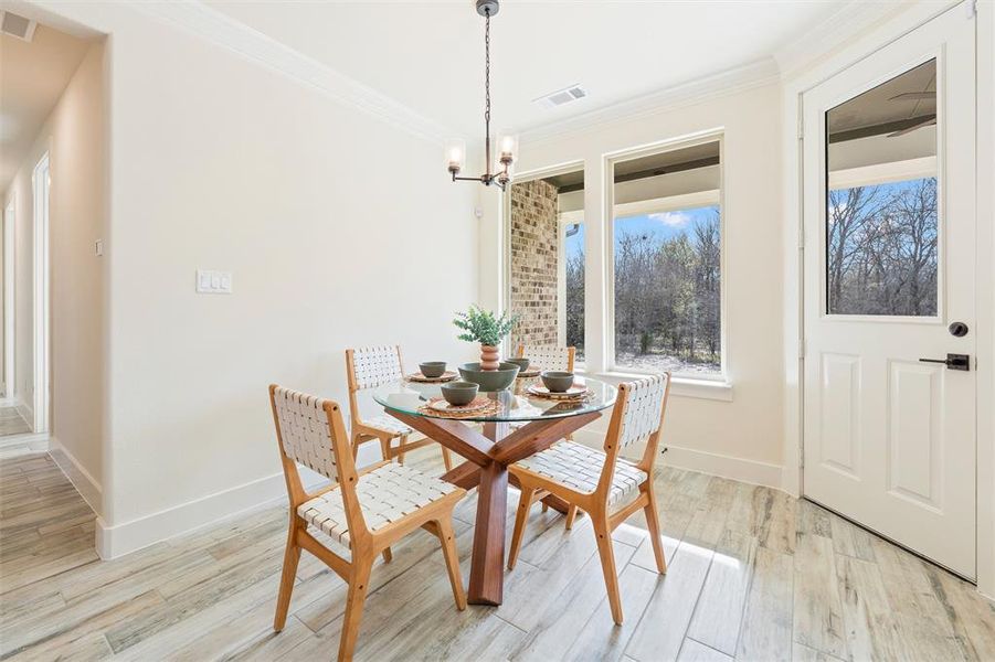 Dining room featuring light wood-style flooring, crown molding, and a chandelier