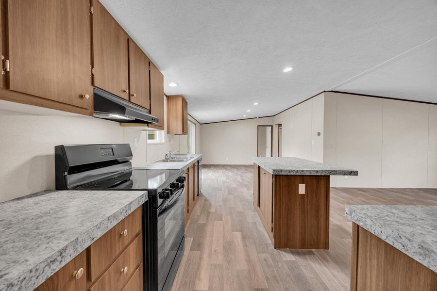 Kitchen featuring black electric range oven, brown cabinetry, light wood-style floors, a kitchen island, and under cabinet range hood