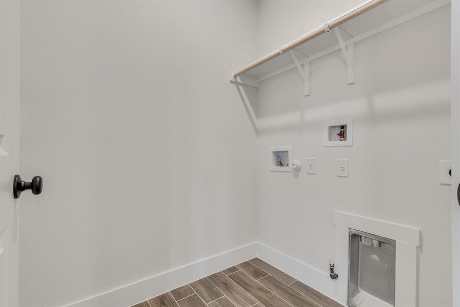 A well-appointed laundry area offers convenient hookups and practical shelving for storage.