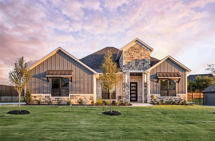 Modern farmhouse style home featuring board and batten siding, stone siding, and a front lawn