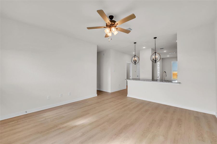 Unfurnished living room with a chandelier, light wood-style floors, ceiling fan, and recessed lighting