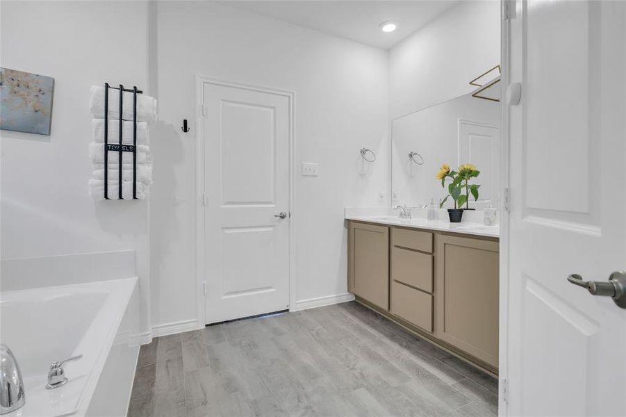 Bathroom featuring hardwood / wood-style floors, vanity, and a tub