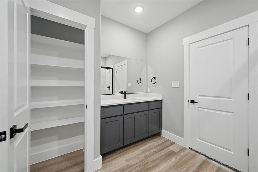 Full bath featuring wood finished floors, vanity, baseboards, and a shower
