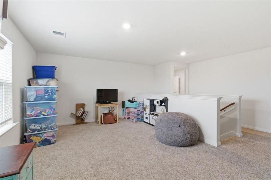 Spacious room featuring carpeting, white walls, and a window with blinds providing natural light