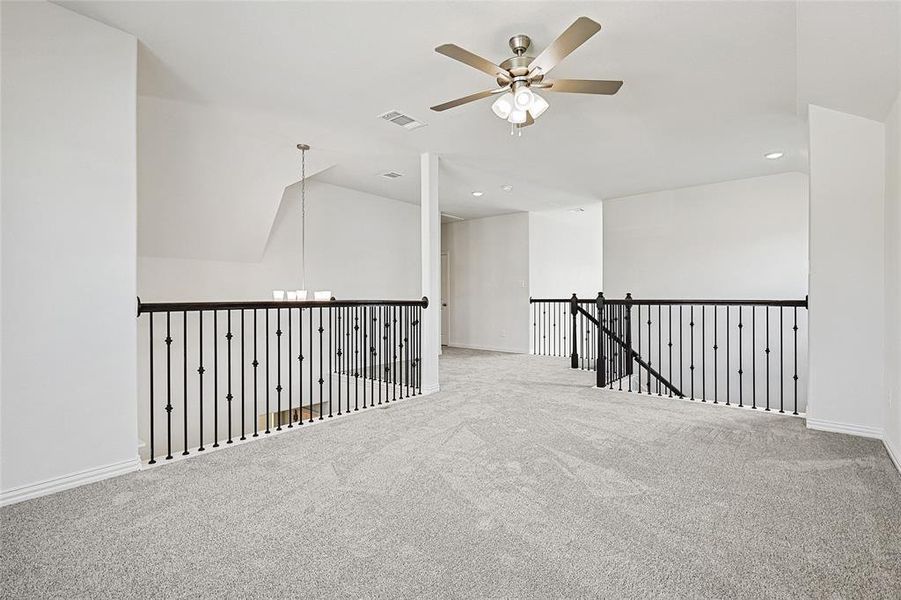 Spare room featuring carpet floors, ceiling fan with notable chandelier, and vaulted ceiling