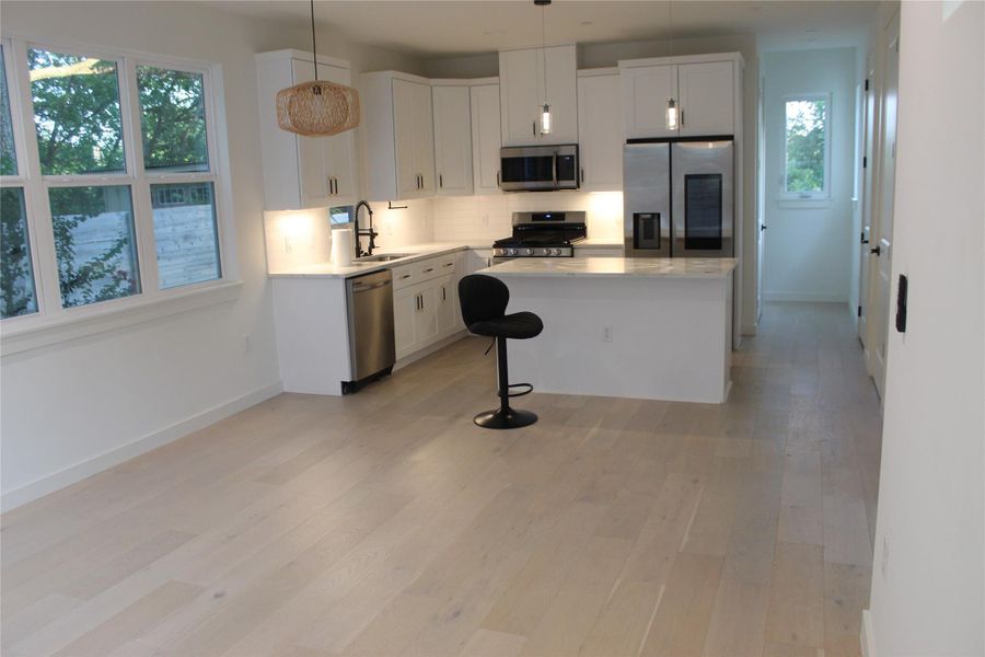A well-lit kitchen with sleek stainless steel appliances, a generous island, and luminous hardwood floors awaits.