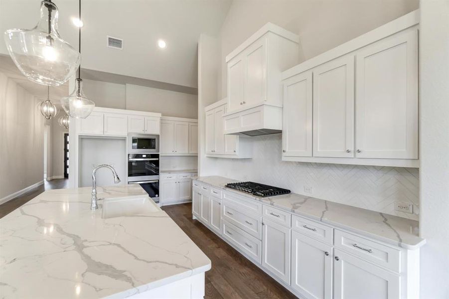 Kitchen with white cabinetry, custom exhaust hood, a center island with sink, dark hardwood / wood-style floors, and appliances with stainless steel finishes