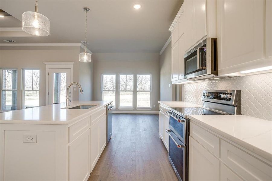 Kitchen featuring pendant lighting, sink, an island with sink, and appliances with stainless steel finishes