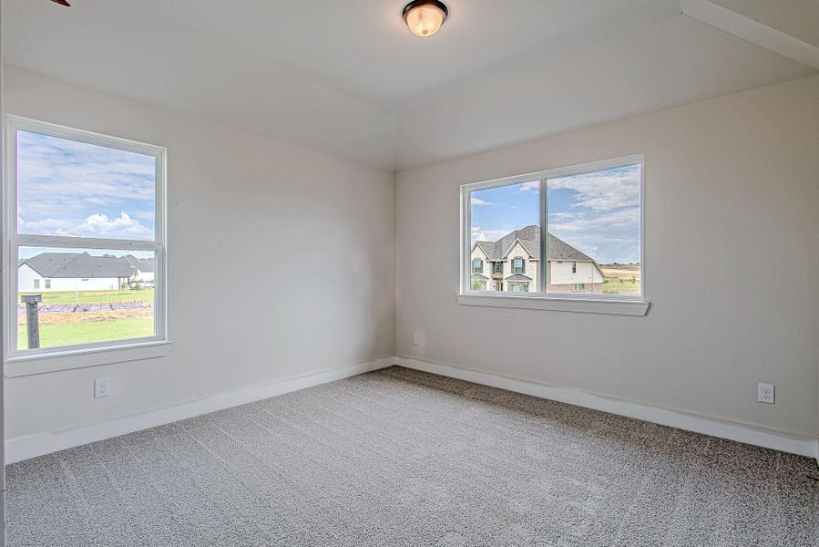 Secondary upstairs bedroom with plush carpeting, dual windows for abundant natural light, and a charming view of the neighborhood.
