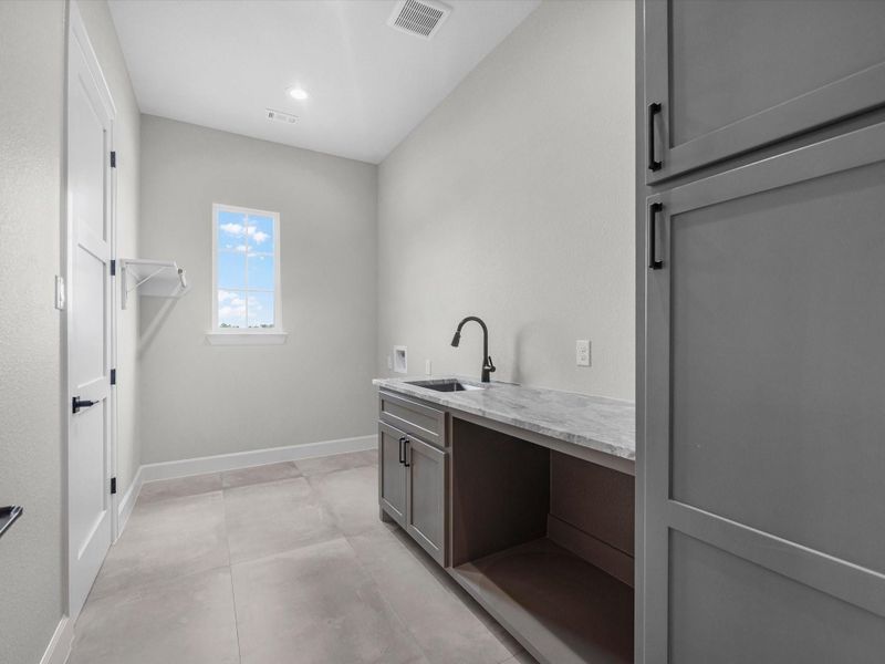 Bright utility room with abundant cabinetry, counter space, and natural light.