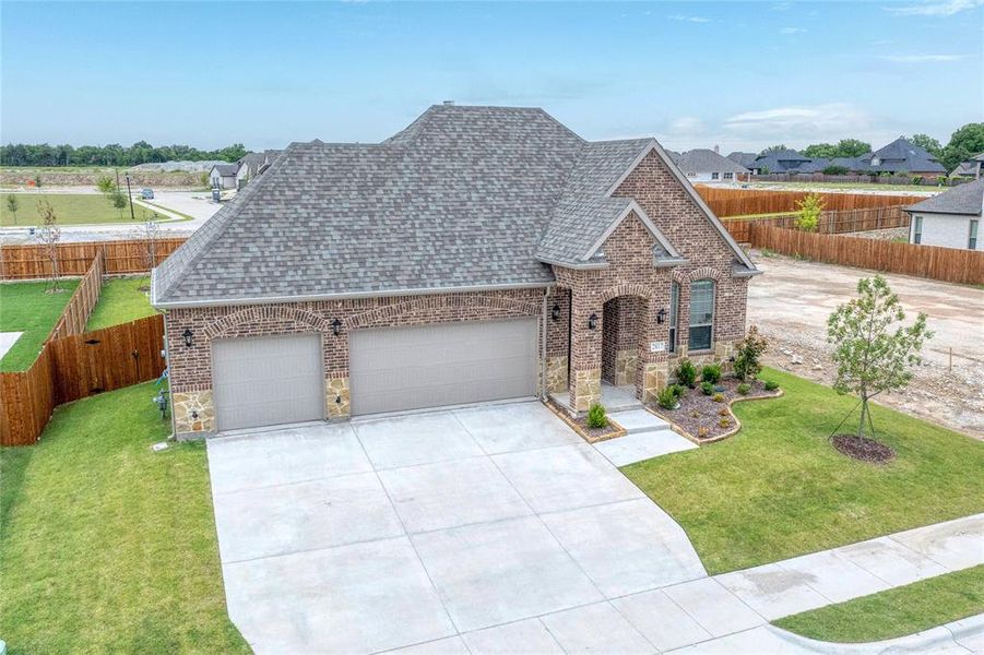 Traditional-style house featuring an attached garage, roof with shingles, concrete driveway, brick siding, and a fenced backyard Traditional-style house featuring an attached garage, roof with shingles, concrete driveway, brick siding, and a fenced backyard