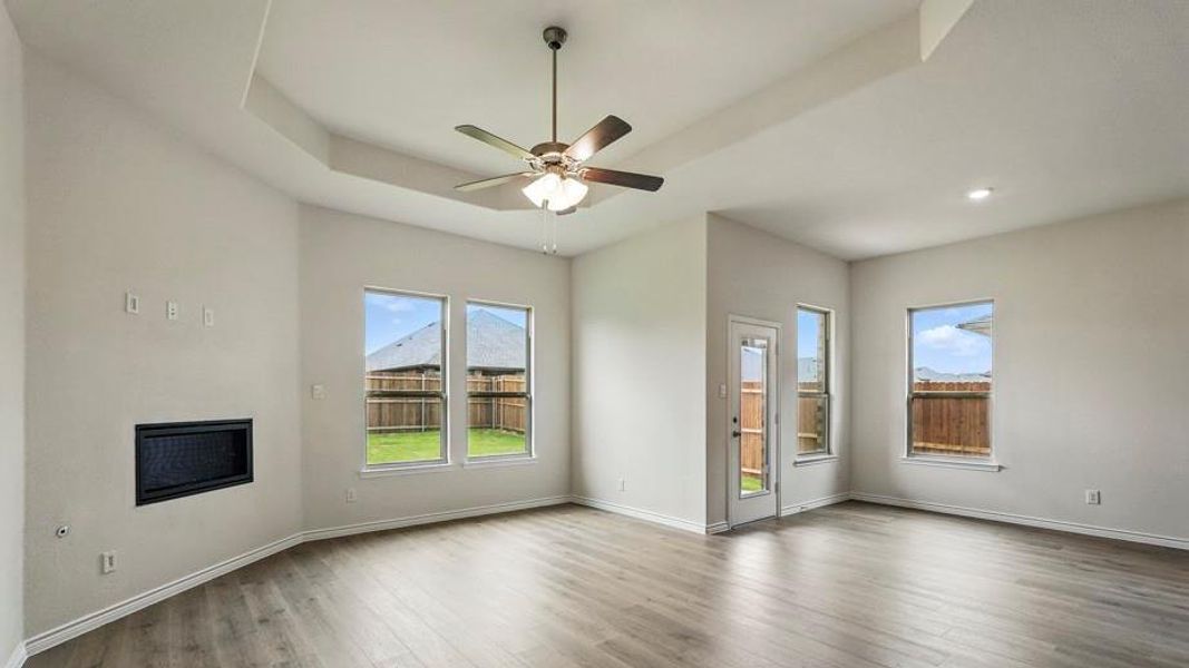 Spacious living area featuring wood-finish flooring, a tray ceiling with a ceiling fan, and recessed lighting