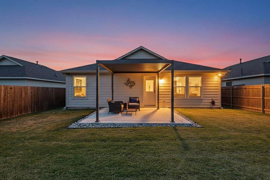 Back of property at dusk featuring a fenced backyard and a patio area Back of property at dusk featuring a fenced backyard and a patio area