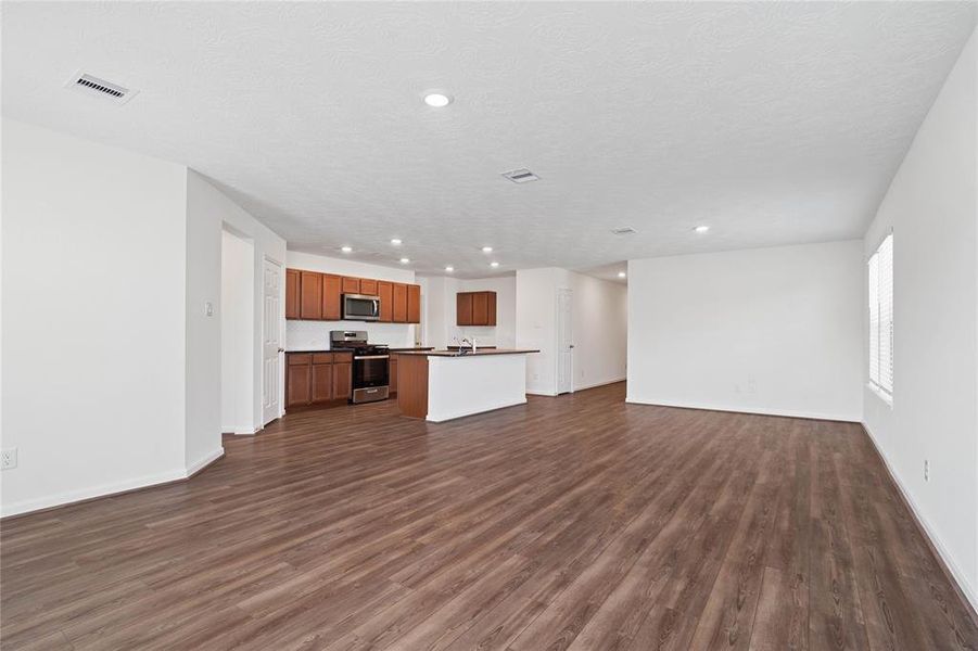 Another view of the Great Room featuring the beautiful vinyl plank flooring, looking into the Kitchen and Dining.