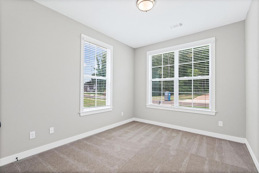 Room featuring two windows with white blinds, neutral carpeting, and light gray wall paint Room featuring two windows with white blinds, neutral carpeting, and light gray wall paint
