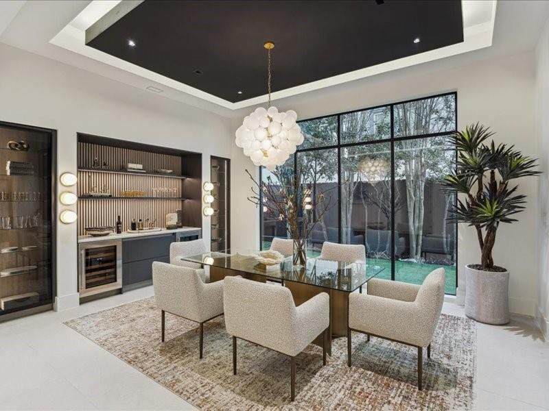 A breathtaking dining room highlighted by a designer chandelier and floor-to-ceiling window that looks out onto a canopy of beautiful trees—an inviting blend of luxury and nature.