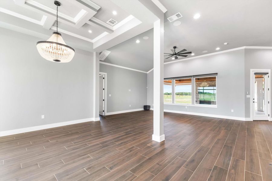 Unfurnished living room with crown molding, baseboards, ceiling fan, a chandelier, and dark wood-style floors Unfurnished living room with crown molding, baseboards, ceiling fan, a chandelier, and dark wood-style floors