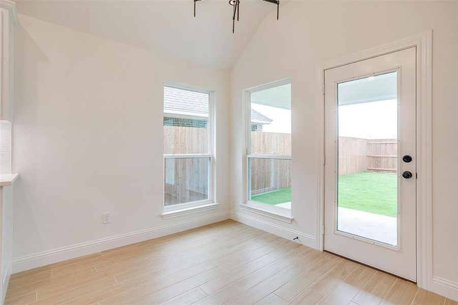 Doorway with light hardwood / wood-style flooring and lofted ceiling