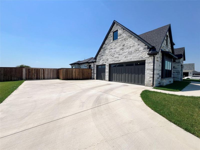 View of property exterior with a garage, stone siding, driveway, and roof with shingles