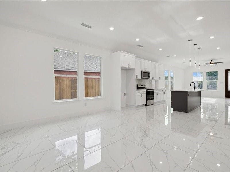 Unfurnished living room featuring ceiling fan, light tile patterned floors, and sink