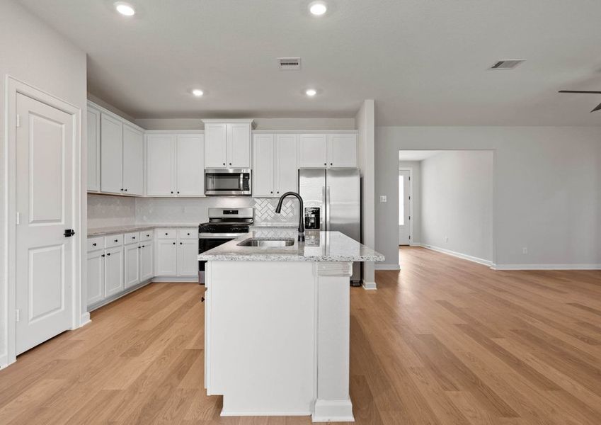 Kitchen with white tile backsplash, white cabinets and granite countertops