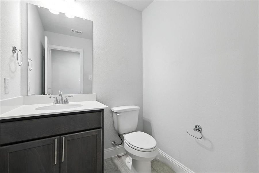 Half bathroom featuring toilet and vanity on second level