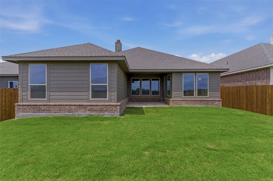 Expansive backyard featuring a lush green lawn, full privacy fencing, and a concrete patio