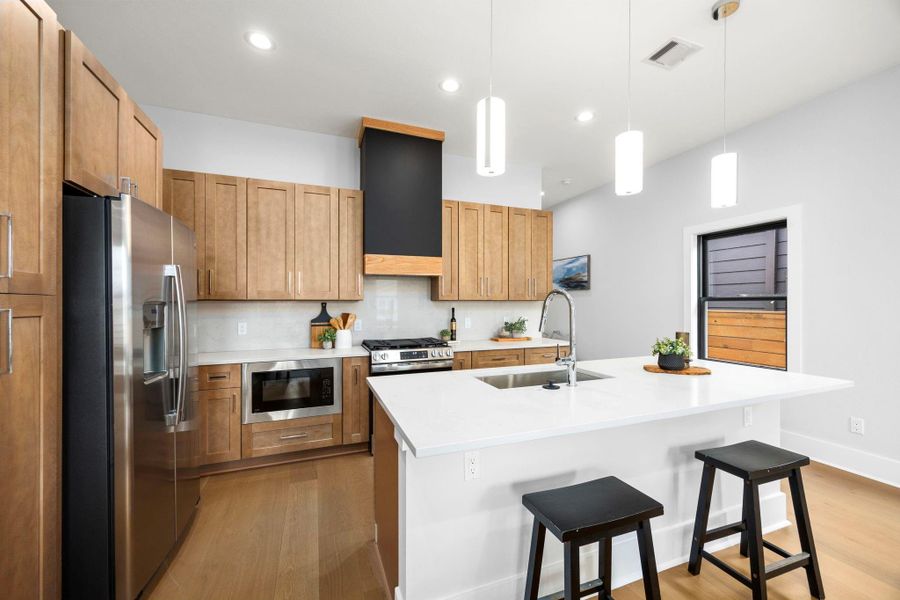 This stunning kitchen has plenty of storage, complemented by a stylish vent hood that adds a modern touch, along with a cleverly hidden microwave built into the lower cabinetry for a seamless look.