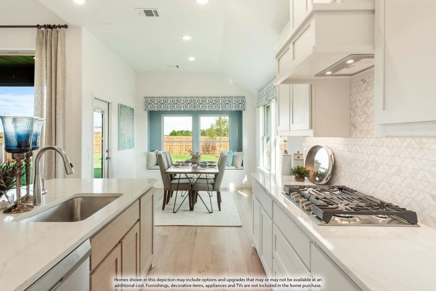 White kitchen with quartz countertops, gas cooktop, and tile backsplash open to dining nook with window seat