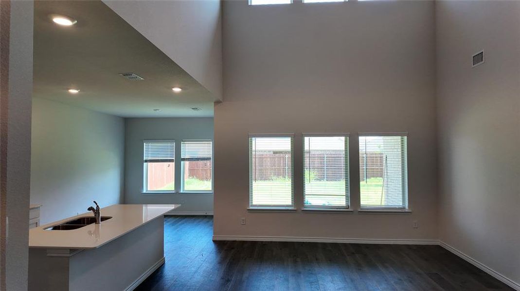 Unfurnished living room featuring dark wood-style floors, recessed lighting, and a high ceiling