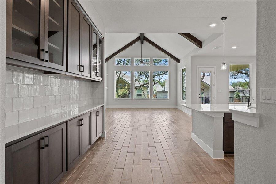 Kitchen featuring healthy amount of natural light, decorative backsplash, dark brown cabinetry, glass insert cabinets, and recessed lighting Kitchen featuring healthy amount of natural light, decorative backsplash, dark brown cabinetry, glass insert cabinets, and recessed lighting