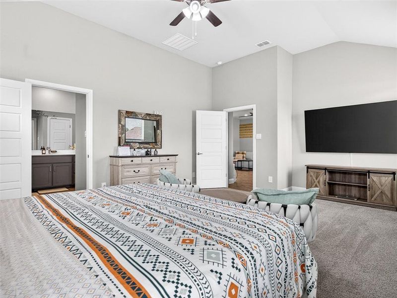 Vaulted ceilings with a ceiling fan, plush carpet flooring, and a barn-door style media console Vaulted ceilings with a ceiling fan, plush carpet flooring, and a barn-door style media console