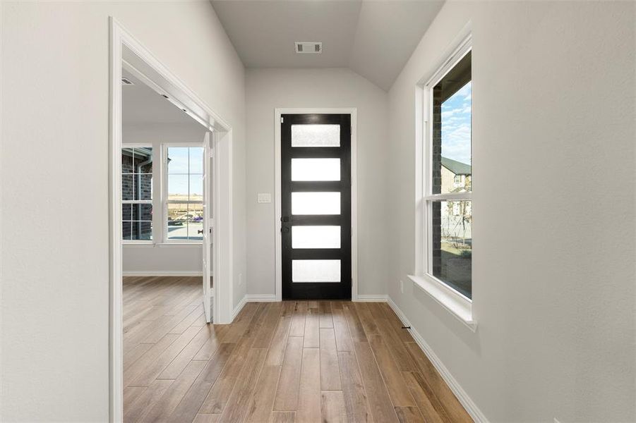 Foyer entrance featuring light wood finished floors, lofted ceiling, and plenty of natural light Foyer entrance featuring light wood finished floors, lofted ceiling, and plenty of natural light