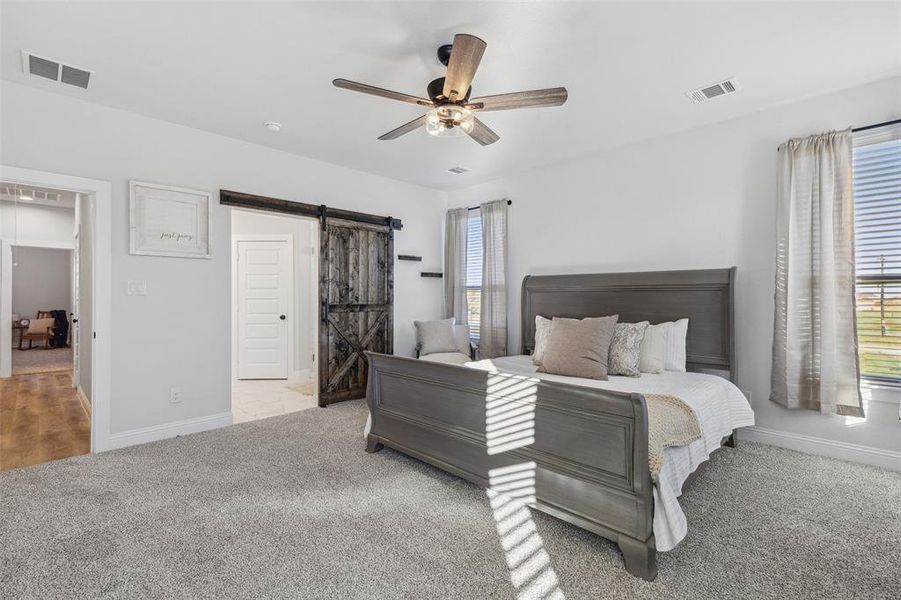 Bedroom with light carpet, a barn door, and ceiling fan