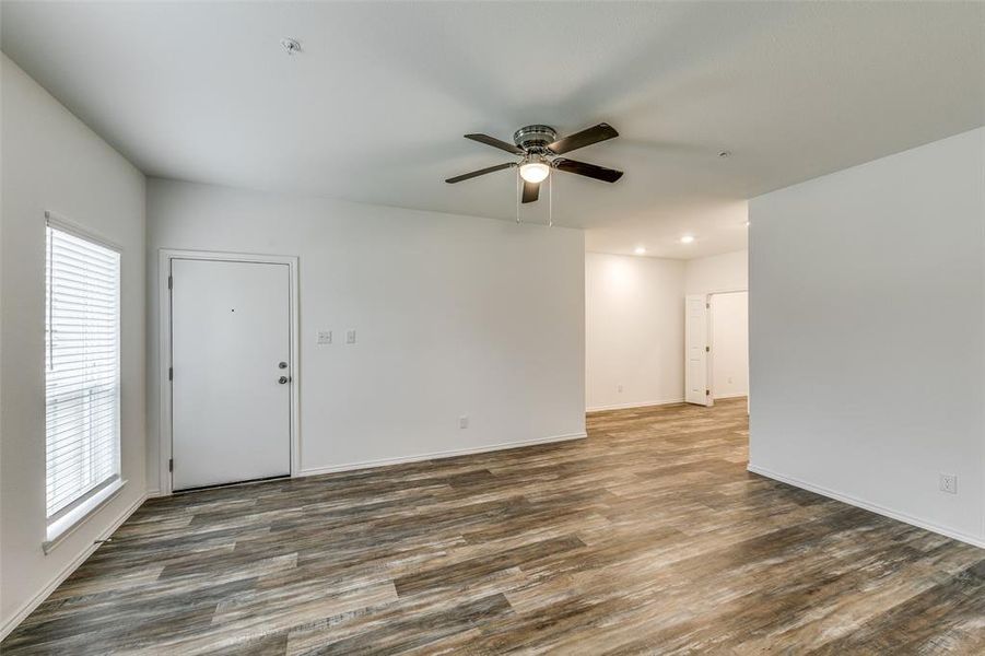 Empty room with dark hardwood / wood-style floors, ceiling fan, and plenty of natural light