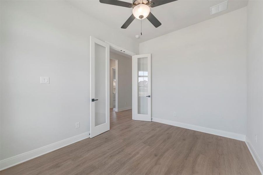 Empty room featuring wood finished floors, a ceiling fan, and french doors